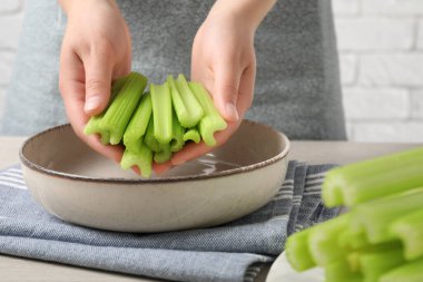 Beyaz masadaki taze kesilmiş kerevizli kadın, yakın plan.