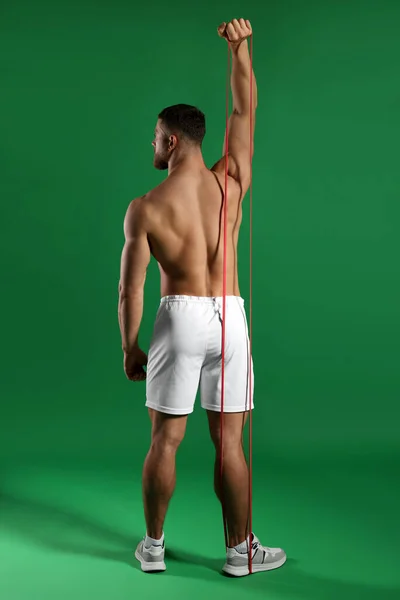 Svalnatý Muž Cvičení Elastickým Odporem Pás Zeleném Pozadí Pohled Zezadu — Stock fotografie