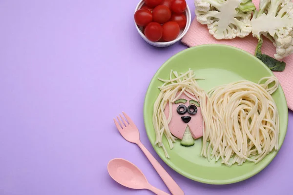 Creative serving for kids. Plate with cute dog made of tasty pasta, sausage and cucumber on violet table, flat lay. Space for text