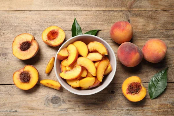 Cut and whole juicy peaches on wooden table, flat lay