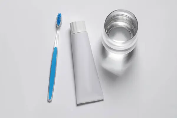 Kunststof Tandenborstel Met Pasta Glas Water Witte Ondergrond Bovenaanzicht — Stockfoto