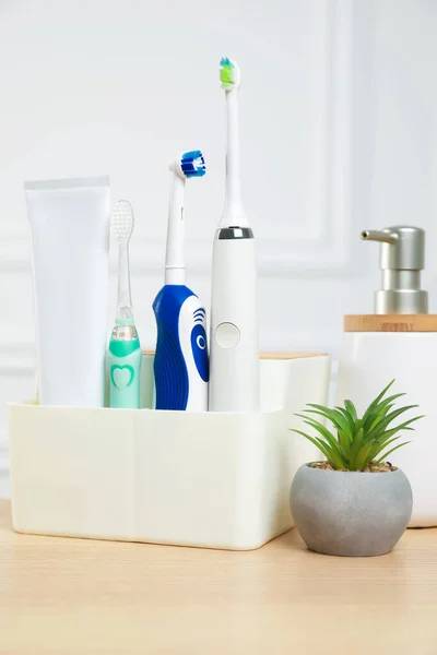 Electric toothbrushes and soap dispenser on wooden table