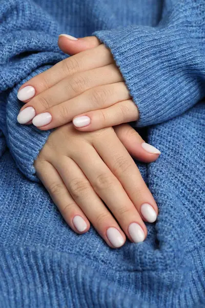 Woman showing her manicured hands with white nail polish, closeup