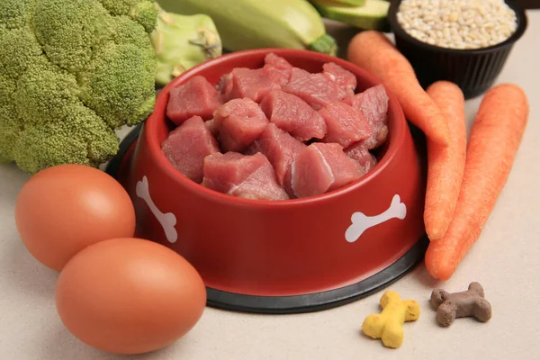 stock image Raw meat in bowl, products and vitamins for pet on beige background, closeup