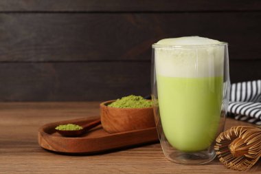 Bir bardak lezzetli kibrit latte, bambu çırpısı ve ahşap masada yeşil toz, metin için yer.