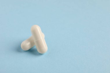 Açık mavi arka planda iki beyaz hap, yakın plan. Metin için boşluk