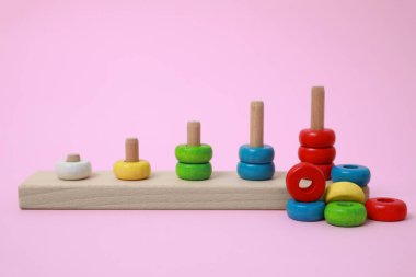 Pembe arka planda tahta parçaları toplayıp saymak. Motor becerileri geliştirmek için eğitici bir oyuncak