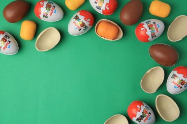 Sveti Vlas, Bulgaristan - 29 Haziran 2023: Yeşil zemin üzerinde Kinder Surprise Eggs ve plastik kapsüller, düz zemin. Metin için boşluk