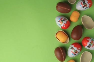 Sveti Vlas, Bulgaristan - 29 Haziran 2023: Açık yeşil zemin üzerinde Kinder Surprise Eggs ve plastik kapsüller, düz zemin. Metin için boşluk