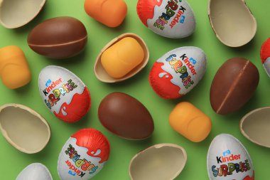Sveti Vlas, Bulgaristan - 29 Haziran 2023: Açık yeşil zemin üzerinde Kinder Sürpriz Yumurtalar ve plastik kapsüller, düz yatar