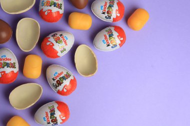 Sveti Vlas, Bulgaristan - 29 Haziran 2023: Mor arka planda Kinder Sürpriz Yumurtalar ve plastik kapsüller, düz konum. Metin için boşluk