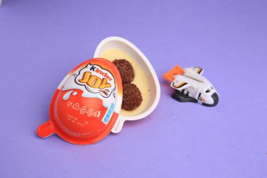 Sveti Vlas, Bulgaristan - 30 Haziran 2023: Tatlı şekerli Kinder Joy Egg ve menekşe arkaplanda oyuncak