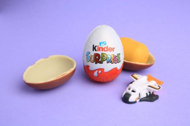 Sveti Vlas, Bulgaristan - 30 Haziran 2023: Anaokulu Sürpriz Yumurtaları, plastik kapsül ve menekşe arka plandaki oyuncak