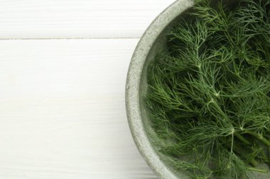 Beyaz ahşap masa üzerinde bir kase taze yeşil dereotu, üst manzara. Metin için boşluk