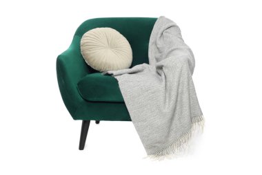 Beyaz yastıklı ve battaniyeli şık rahat bir koltuk.