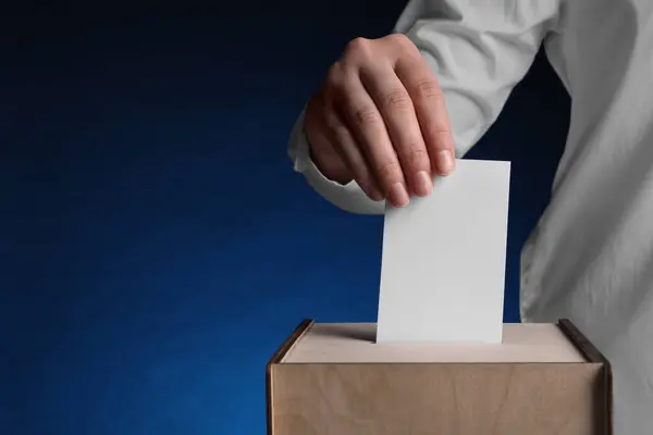 stock image Woman putting her vote into ballot box on dark blue background, closeup. Space for text