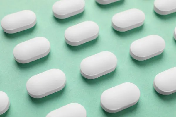 Viele Weiße Pillen Auf Grünem Hintergrund Nahaufnahme — Stockfoto