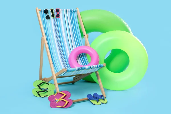 Deck chair and beach accessories on light blue background