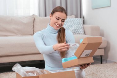 Evde paketleri açan mutlu kadın. Çevrimiçi mağaza