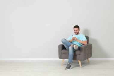 Mutlu adam koltukta oturuyor ve akıllı telefonu içeride kullanıyor, mesaj atmak için yer var.