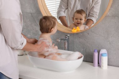 Babası küçük bebeğini evde lavaboda yıkıyor.