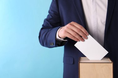 Adam oyunu açık mavi arka planda sandığa koyuyor, yakın plan. Metin için boşluk
