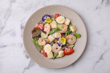 Beyaz mermer masada karidesli leziz Sezar salatası.