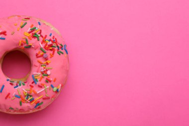 Tatlı jöleli donut pembe arka plan üzerine serpiştirilmiş, üst manzara ve metin için alan. Lezzetli şekerlemeler.