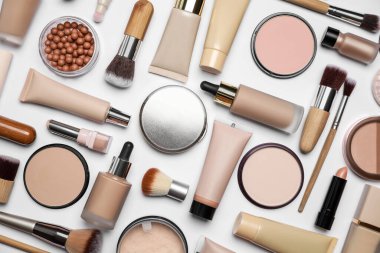 Beyaz arka planda yüz pudraları ve diğer makyaj ürünleri, düz yatıyordu