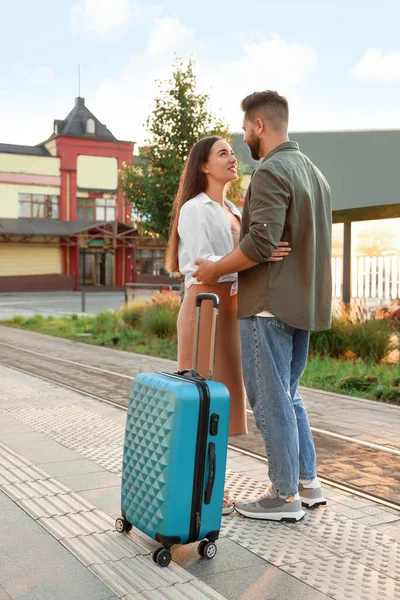 Long-distance relationship. Beautiful young couple with suitcase at railway station outdoors