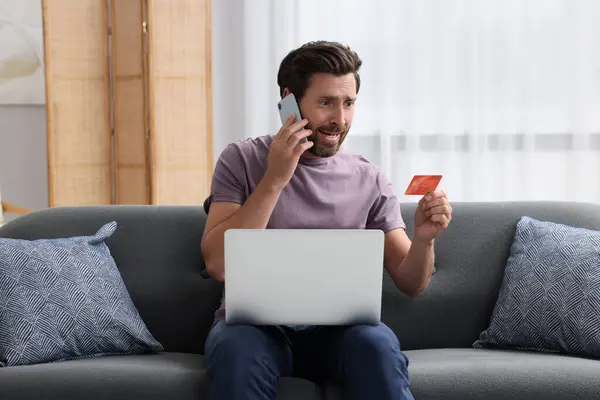 Emocjonalny Człowiek Kartą Kredytową Laptopem Rozmawiający Przez Telefon Domu Uważaj — Zdjęcie stockowe