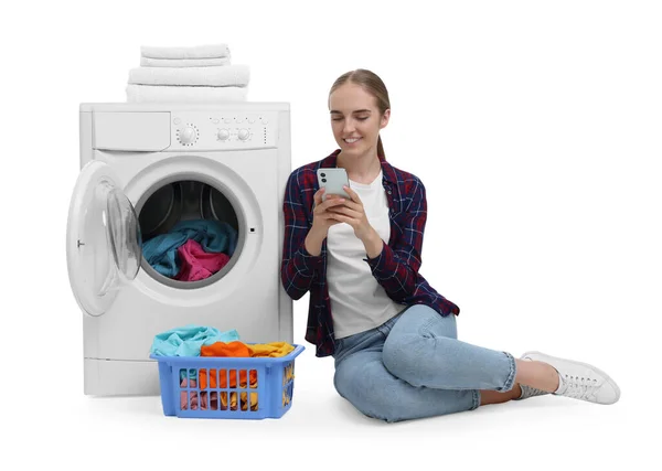 白い背景に対して洗濯機の近くでスマートフォンを使用して美しい若い女性 — ストック写真