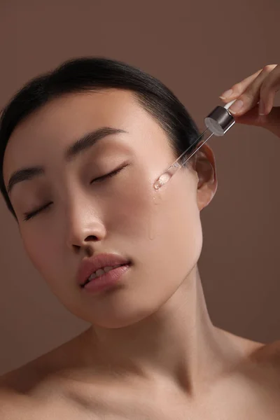 Wanita Muda Cantik Menerapkan Serum Kosmetik Wajahnya Pada Latar Belakang — Stok Foto