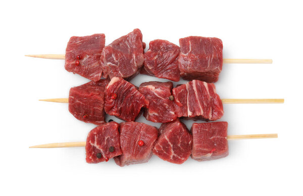 Wooden skewers with cut fresh beef meat isolated on white, top view
