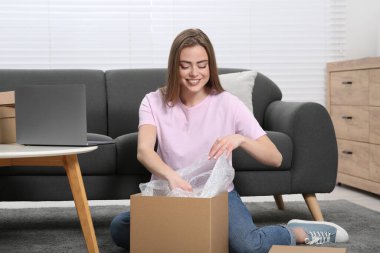 Evde paketleri açan mutlu kadın. Çevrimiçi mağaza