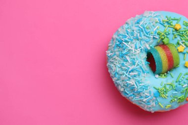 Tatlı jöleli donut pembe arka plan üzerine serpiştirilmiş, üst manzara ve metin için alan. Lezzetli şekerlemeler.