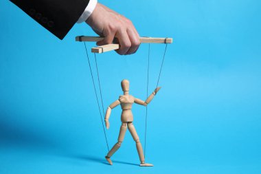 Kuklanın iplerini çeken adam açık mavi arka planda, yakın plan