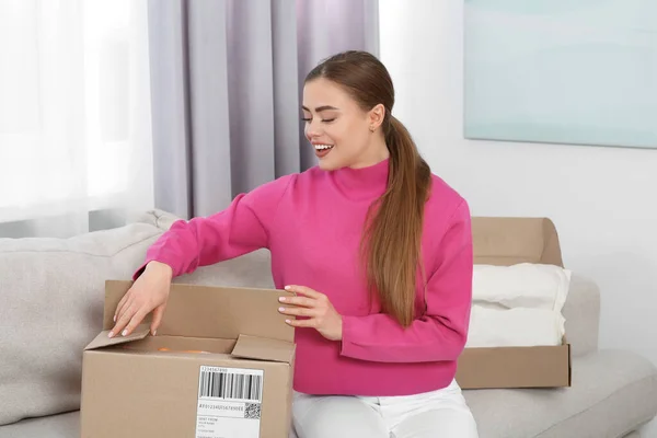 Emotional woman unpacking parcel at home. Online store