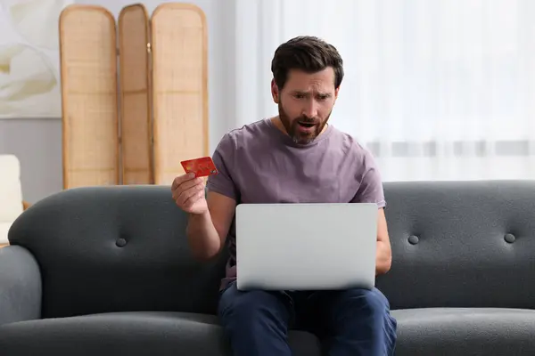 Emocjonalny Człowiek Laptopem Kartą Kredytową Sofie Domu Uważaj Oszustwo — Zdjęcie stockowe