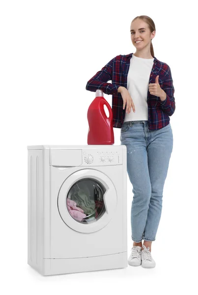 白い背景の洗濯機の近くに親指を示す洗剤を持つ美しい若い女性 — ストック写真