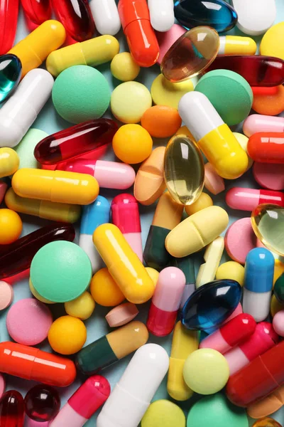 Açık mavi arka planda bir sürü farklı hap var.