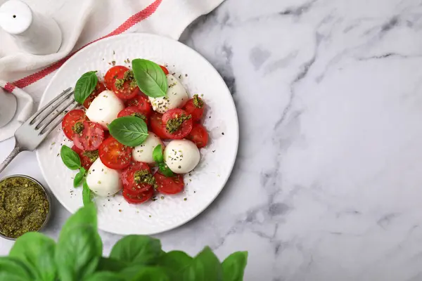 Domatesli Caprese salatası, mozzarella topları ve beyaz mermer masada servis edilen fesleğen. Metin için boşluk