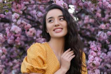 Bahar günü çiçek açan sakura ağacının yanında güzel bir kadın.