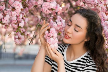 Bahar günü çiçek açan sakura ağacının yanında güzel bir kadın.