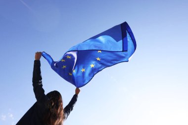 Avrupa Birliği bayrağını açık havada mavi gökyüzüne doğru tutan kadın, düşük açılı bakış açısı