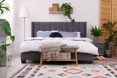 Çift kişilik yatağı ve güzel yeşil çiçekleri olan şık bir yatak odası. Modern iç mimari