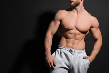 Kaslı adam siyah arka planda kaslarını gösteriyor, yakın plan ve mesaj için boşluk. Seksi vücut.