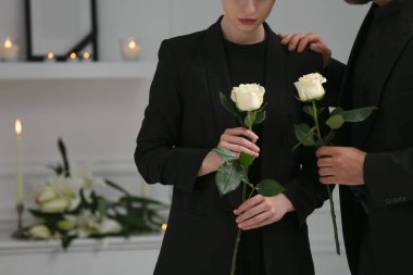 Beyaz güller içinde yas tutan bir çift, yakın çekim ve mesaj için yer. Cenaze töreni.
