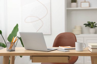 Merkez ofis. İç mekandaki ahşap masada dizüstü bilgisayarı ve kırtasiyesi olan şık bir iş yeri.