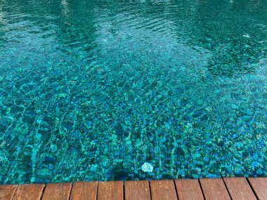 Yüzme havuzunda berrak dalgalı su ve açık havada ahşap güverte. Metin için boşluk